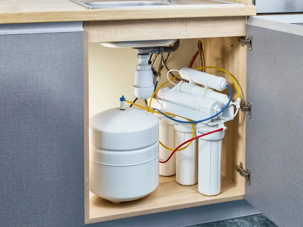 Technician repairing a reverse osmosis water filter system in a Toronto home, using tools to adjust the filtration unit and check for leaks.