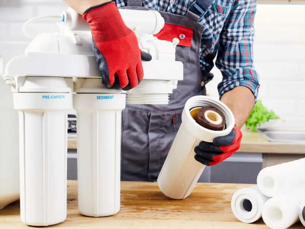 Technician performing an emergency repair on a reverse osmosis water filter system, adjusting valves and inspecting connections.